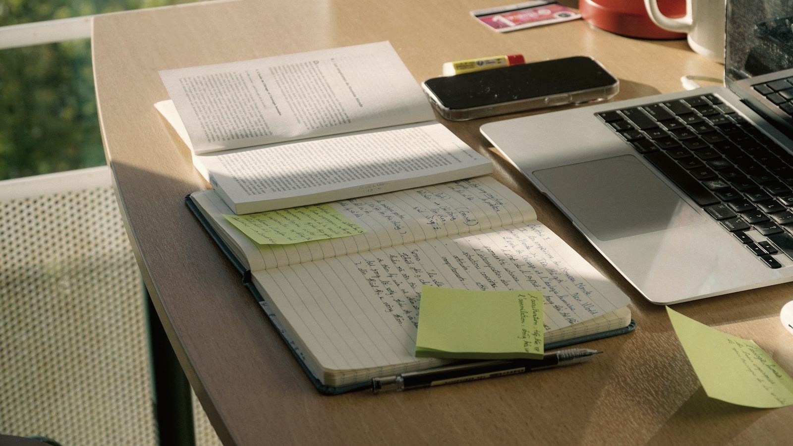 Handwritten notes and sticky notes next to a laptop